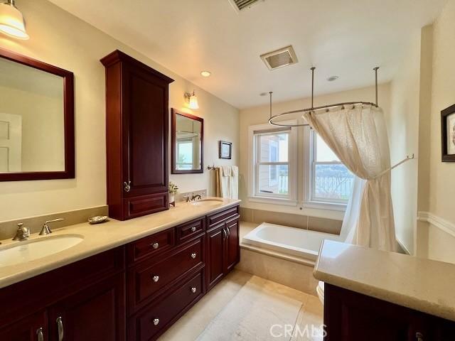 bathroom with tiled tub and vanity