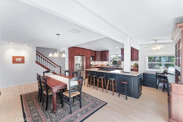 dining room featuring lofted ceiling, ceiling fan with notable chandelier, and light hardwood / wood-style floors