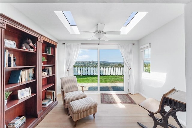 sitting room featuring a skylight, light hardwood / wood-style floors, and ceiling fan