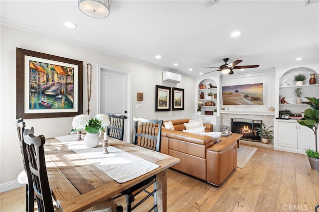 dining room with crown molding, a wall unit AC, light hardwood / wood-style floors, and built in shelves