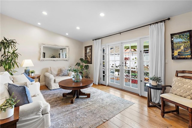 living room featuring vaulted ceiling, light hardwood / wood-style floors, and french doors