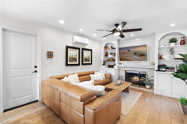 living room with crown molding, light hardwood / wood-style flooring, built in features, ceiling fan, and a wall mounted AC