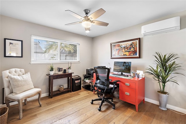 home office with an AC wall unit, ceiling fan, and light wood-type flooring