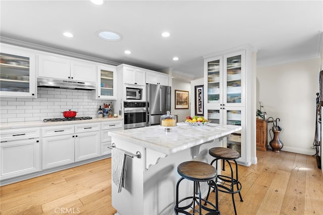 kitchen featuring ornamental molding, a center island, white cabinets, and appliances with stainless steel finishes