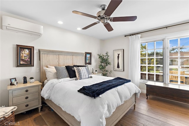 bedroom featuring hardwood / wood-style flooring, ceiling fan, and a wall unit AC