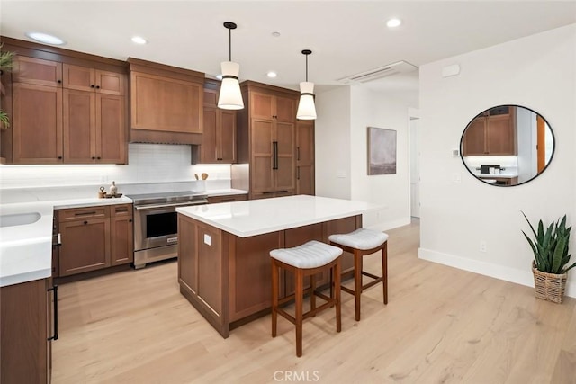 kitchen featuring high end range, hanging light fixtures, custom exhaust hood, a center island, and light wood-type flooring