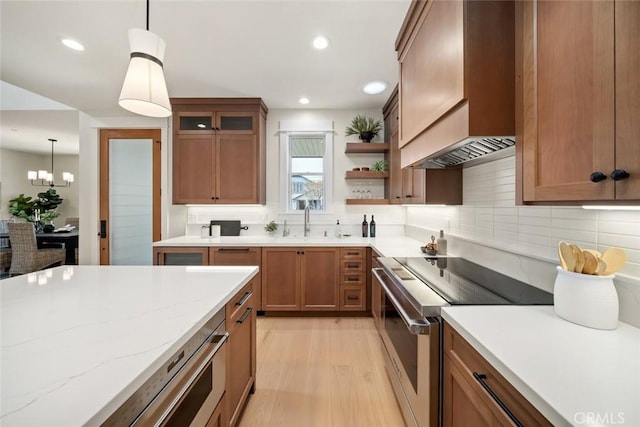 kitchen with stainless steel range, decorative light fixtures, custom exhaust hood, and sink