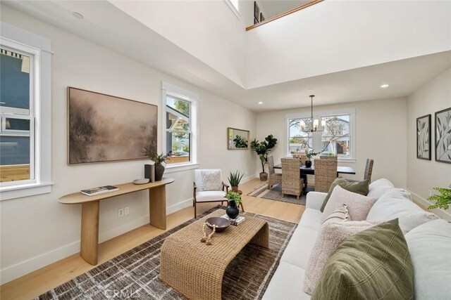 living room with hardwood / wood-style flooring, a wealth of natural light, and an inviting chandelier