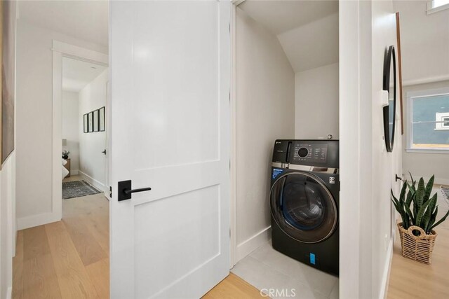 clothes washing area featuring washer / clothes dryer and light hardwood / wood-style floors