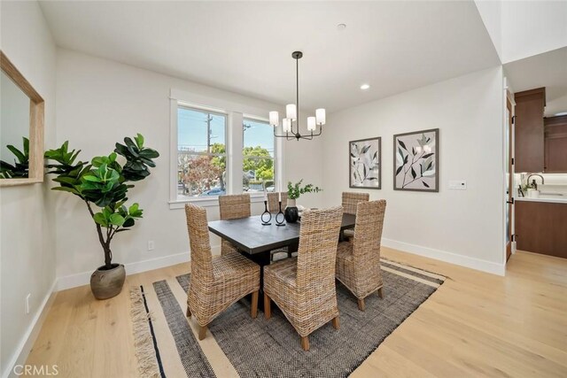 dining space with an inviting chandelier, light hardwood / wood-style floors, and sink