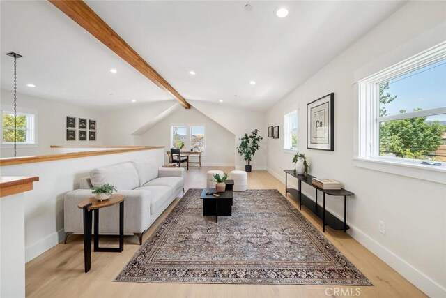 living room featuring light wood-type flooring, a wealth of natural light, and beam ceiling