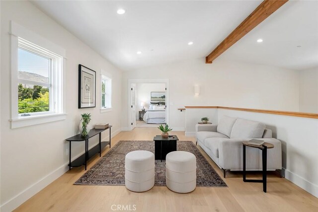 living room featuring vaulted ceiling with beams and light hardwood / wood-style flooring