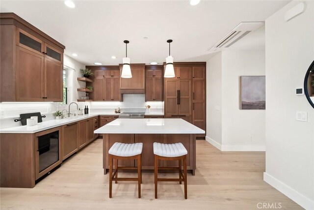 kitchen featuring a kitchen island, decorative light fixtures, a kitchen bar, decorative backsplash, and light wood-type flooring