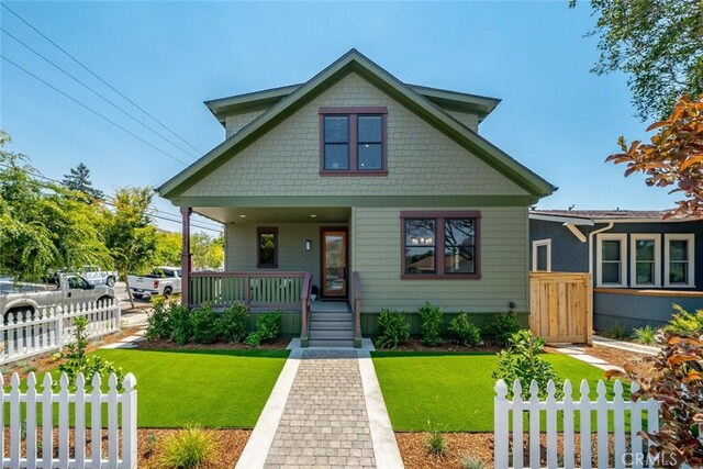 bungalow featuring covered porch and a front lawn