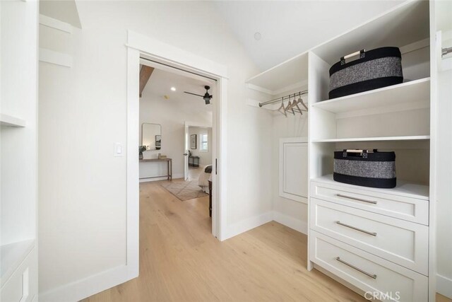 walk in closet featuring light hardwood / wood-style flooring, vaulted ceiling, and ceiling fan