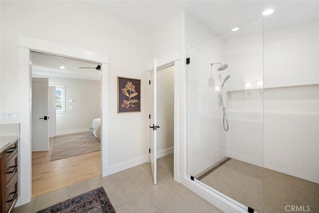 bathroom featuring hardwood / wood-style flooring, tiled shower, and vanity