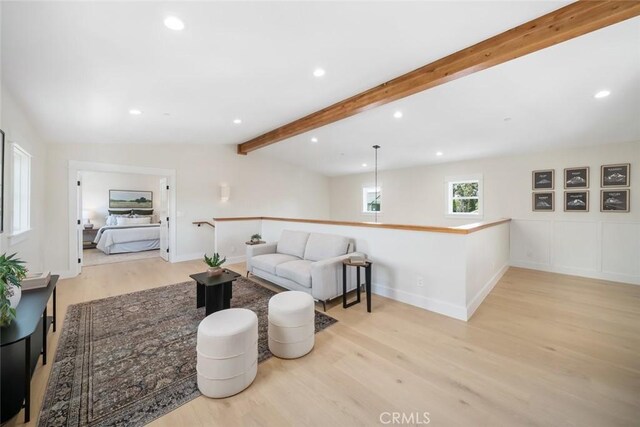 living room featuring lofted ceiling with beams and light hardwood / wood-style floors