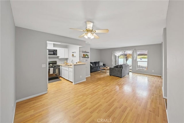 unfurnished living room featuring sink, light hardwood / wood-style floors, and ceiling fan