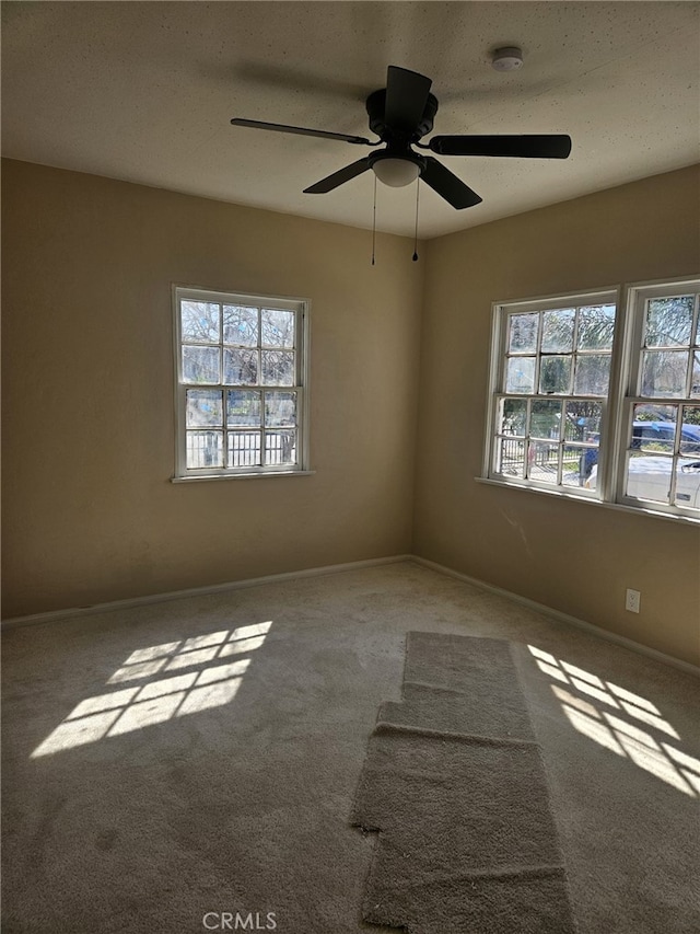 unfurnished room featuring carpet, baseboards, and a ceiling fan