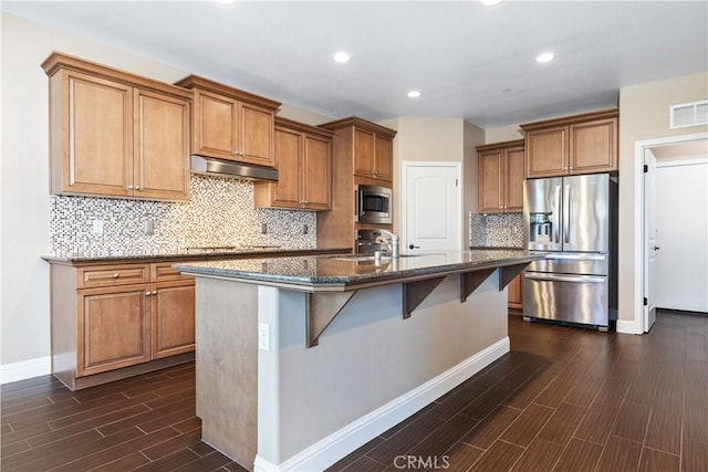 kitchen featuring sink, stainless steel appliances, a kitchen breakfast bar, tasteful backsplash, and a center island with sink