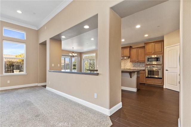 kitchen featuring appliances with stainless steel finishes, a breakfast bar, decorative light fixtures, tasteful backsplash, and a notable chandelier