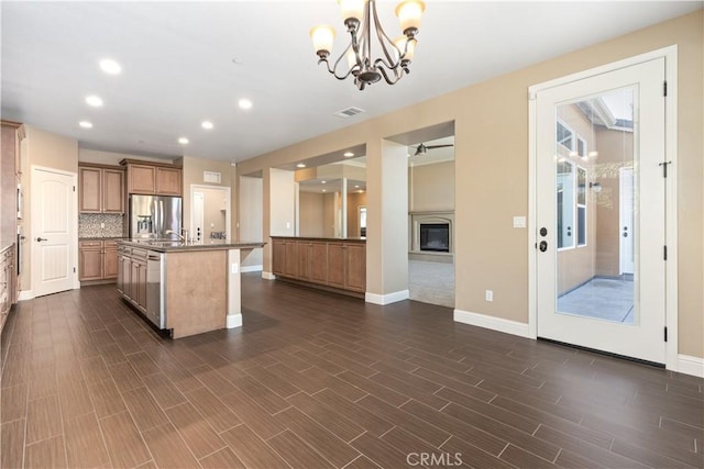 kitchen featuring decorative light fixtures, appliances with stainless steel finishes, dark hardwood / wood-style flooring, an island with sink, and backsplash