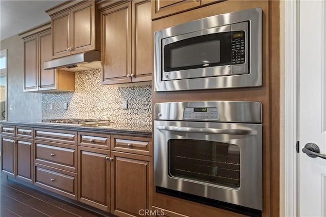 kitchen featuring appliances with stainless steel finishes, dark wood-type flooring, and backsplash