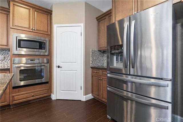 kitchen with dark hardwood / wood-style flooring, backsplash, stainless steel appliances, and dark stone counters