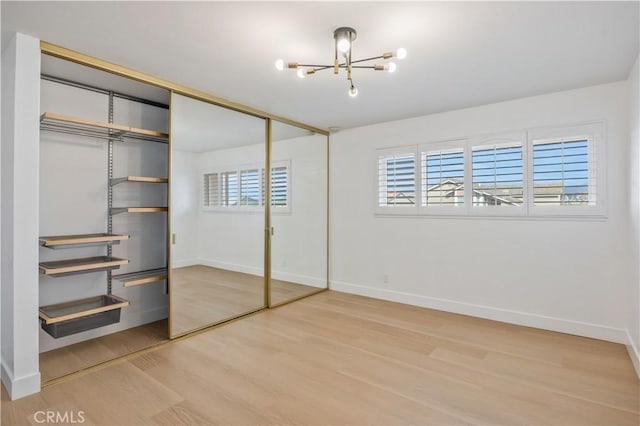 unfurnished bedroom with multiple windows, hardwood / wood-style floors, and a chandelier