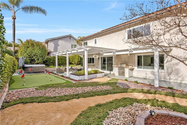 back of house with a hot tub, an outdoor kitchen, a patio area, and a pergola