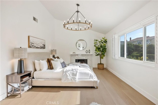 bedroom featuring wood-type flooring, lofted ceiling, and an inviting chandelier