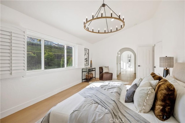 bedroom featuring vaulted ceiling, light hardwood / wood-style floors, and a chandelier