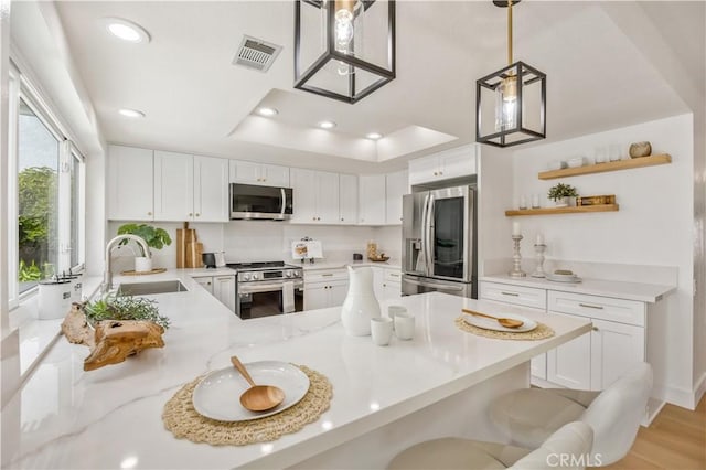 kitchen with white cabinetry, sink, a kitchen breakfast bar, kitchen peninsula, and stainless steel appliances