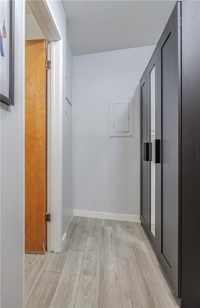 hallway featuring electric panel and light hardwood / wood-style flooring