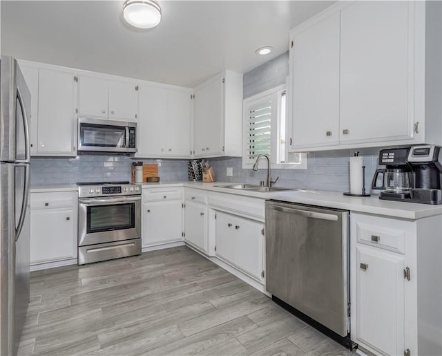 kitchen with white cabinetry, sink, backsplash, and stainless steel appliances