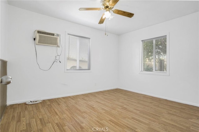 empty room with light wood-style floors, ceiling fan, baseboards, and an AC wall unit