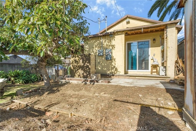 back of house with fence, a patio, and stucco siding