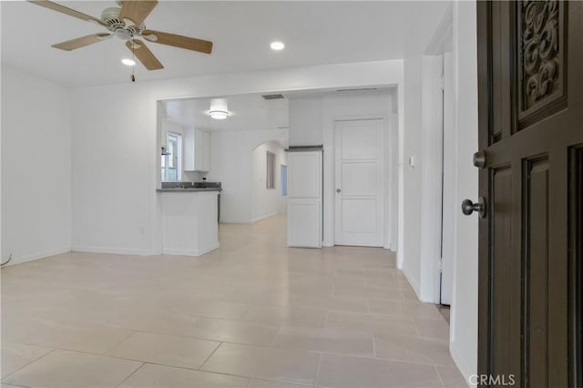 interior space with arched walkways, visible vents, ceiling fan, and baseboards