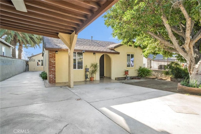 exterior space featuring a patio, fence, and stucco siding