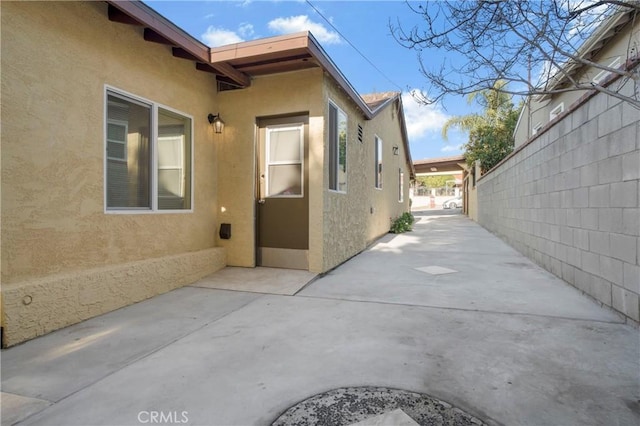 view of property exterior featuring fence, a patio, and stucco siding