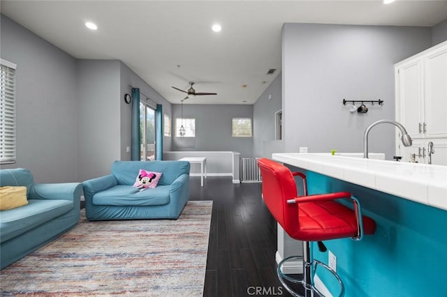 living room featuring ceiling fan, dark hardwood / wood-style flooring, and sink