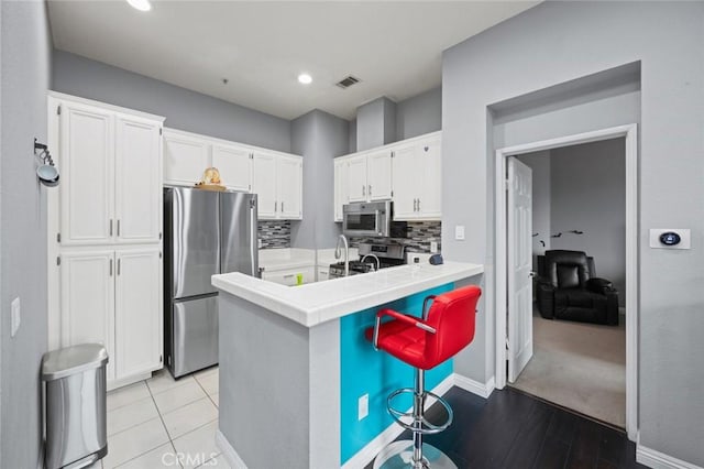 kitchen featuring white cabinetry, tile counters, tasteful backsplash, and appliances with stainless steel finishes