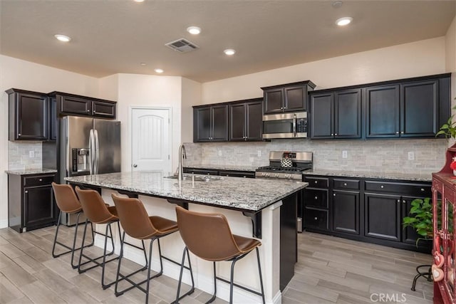 315 Timberline Way S, Madera, CA 93636 - kitchen with stainless steel appliances, a sink, light wood-style flooring, light stone counters, and recessed lighting
