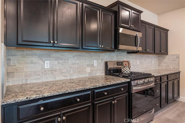 315 Timberline Way S, Madera, CA 93636 - kitchen featuring appliances with stainless steel finishes, light stone countertops, decorative backsplash, and light wood-style flooring