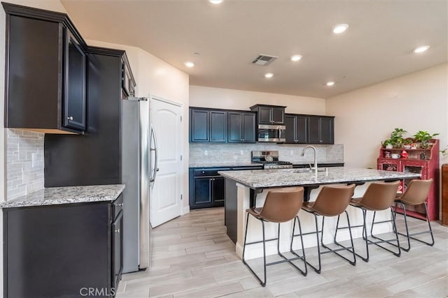 315 Timberline Way S, Madera, CA 93636 - kitchen with stainless steel appliances, decorative backsplash, a breakfast bar, light stone countertops, and recessed lighting