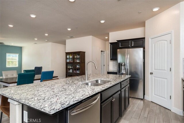 315 Timberline Way S, Madera, CA 93636 - kitchen with stainless steel appliances, a sink, a kitchen island with sink, light stone countertops, and recessed lighting