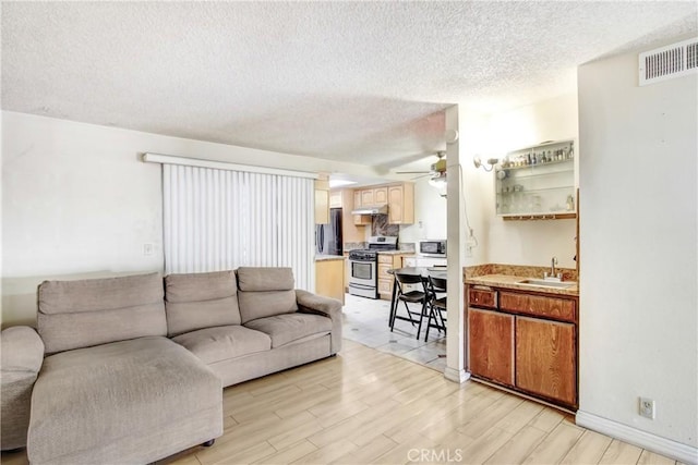 living room featuring sink, a textured ceiling, light hardwood / wood-style floors, and ceiling fan