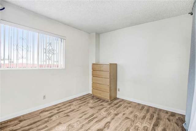 empty room with hardwood / wood-style floors and a textured ceiling