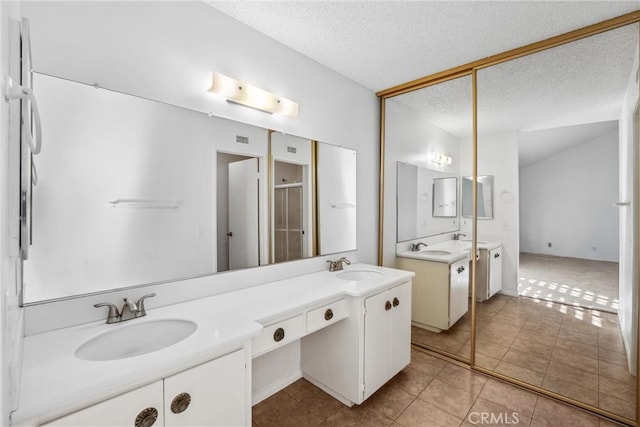 bathroom featuring vanity, an enclosed shower, tile patterned flooring, and a textured ceiling