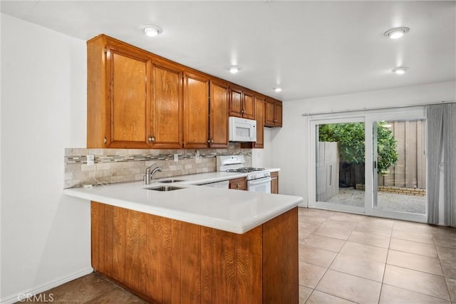 kitchen featuring sink, backsplash, white appliances, and kitchen peninsula